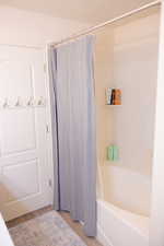 Bathroom featuring shower / bath combination with curtain and wood finished floors