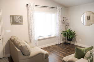 Living area with baseboards, dark wood-style flooring, a wealth of natural light, and lofted ceiling