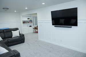 Carpeted living room featuring a decorative wall, a wainscoted wall, and recessed lighting
