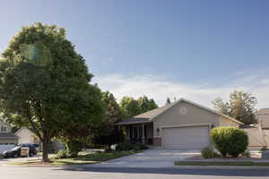 View of front of home featuring a garage, concrete driveway, brick siding, and stucco siding