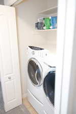 Clothes washing area featuring washing machine and dryer, laundry area, and light tile patterned floors