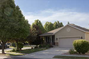 View of front of home with a garage, driveway, brick siding, stucco siding, and a front lawn