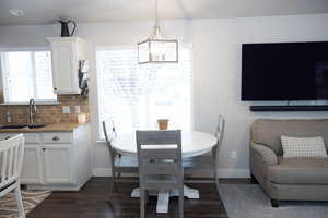 Dining room with dark wood finished floors, baseboards, and a chandelier