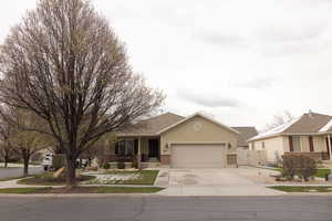 Ranch-style home featuring a gate, a garage, stucco siding, brick siding, and driveway