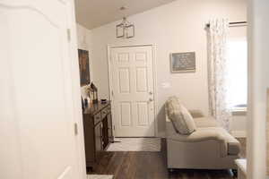 Entrance foyer with dark wood-type flooring, baseboards, and vaulted ceiling