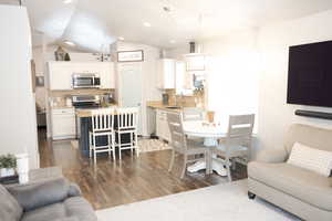 Living room featuring dark wood-type flooring, lofted ceiling, and recessed lighting