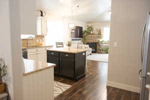 Kitchen featuring backsplash, a sink, dark wood finished floors, stainless steel appliances, and white cabinets