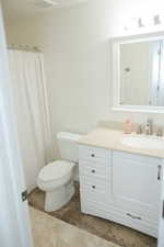 Full bath featuring curtained shower, toilet, and vanity