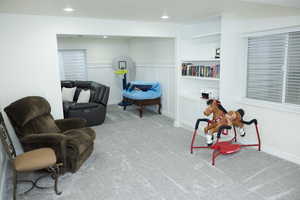 Living area featuring a wainscoted wall, carpet floors, recessed lighting, and a decorative wall