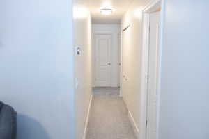 Hallway featuring baseboards and light carpet