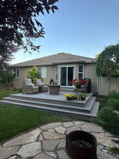 Rear view of house featuring a wooden deck, fence, and an outdoor living space with a fire pit