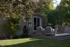 Back of house with a deck and a lawn