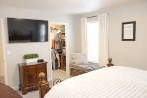 Bedroom featuring baseboards, a walk in closet, a closet, and carpet flooring