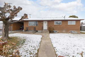View of front of property featuring brick siding, fence, and a carport