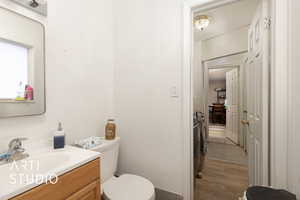 Half bath with toilet, vanity, and wood finished floors
