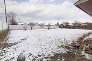 Yard covered in snow featuring a fenced backyard