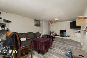 Living area with a textured ceiling, wood finished floors, and a stone fireplace