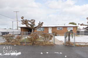 Single story home with brick siding, a fenced front yard, and a carport