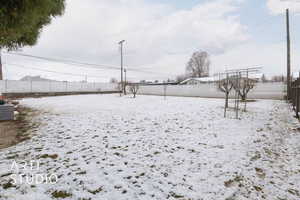 Yard layered in snow featuring cooling unit and a fenced backyard