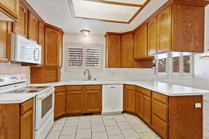Kitchen featuring white appliances, light countertops, a sink, and a peninsula