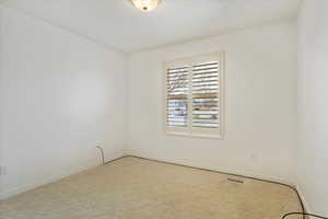 Carpeted spare room featuring baseboards and visible vents
