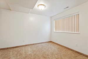 Empty room with baseboards, visible vents, carpet, and a textured ceiling