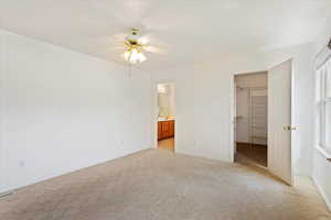 Unfurnished bedroom with a closet, visible vents, baseboards, light carpet, and a walk in closet