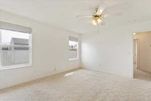 Spare room featuring baseboards, light colored carpet, and ceiling fan