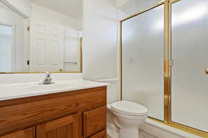 Bathroom featuring vanity, toilet, and a shower stall