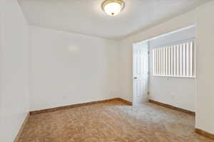 Carpeted spare room with baseboards and a textured ceiling