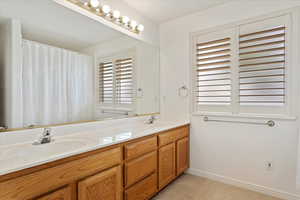 Bathroom featuring double vanity, a sink, and baseboards