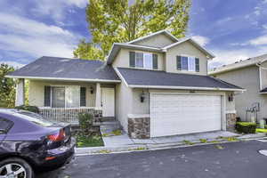Traditional-style home with covered porch, roof with shingles, and a garage.