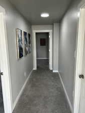 Hallway featuring dark carpet and baseboards