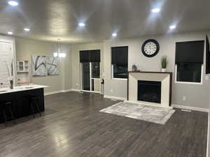 Living area with a chandelier, recessed lighting, dark wood-style flooring, and baseboards