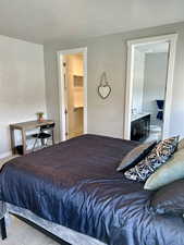 Carpeted bedroom featuring ensuite bathroom, a sink, and a walk in closet