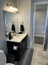 Bathroom featuring visible vents, baseboards, toilet, vanity, and wood finished floors