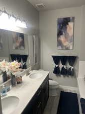 Bathroom with toilet, wood finished floors, a sink, and visible vents