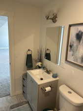 Basement Bathroom with toilet, vanity, marble finish floor, and baseboards