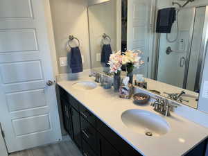 Master Bathroom featuring a shower stall, double vanity, a sink, and wood finished floors