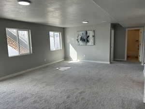 Extra large living room with carpet flooring, visible vents, a textured ceiling, and baseboards