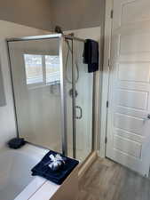 Bathroom featuring a stall shower, wood finished floors, and a tub to relax in