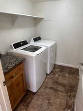 Washroom featuring baseboards, cabinet space, separate washer and dryer, and stone finish floor