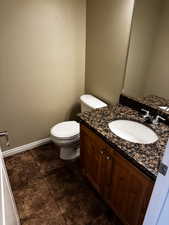 Bathroom featuring baseboards, toilet, and vanity