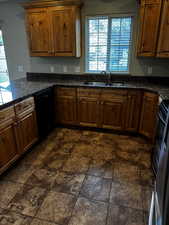 Kitchen featuring a sink, dishwasher, a peninsula, brown cabinetry, and range