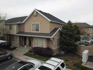 Traditional-style home featuring uncovered parking, stucco siding, and stone siding