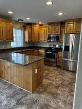 Kitchen with recessed lighting, stainless steel appliances, a sink, a peninsula, and brown cabinets