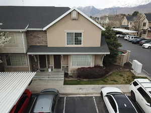 View of front facade featuring stone siding, stucco siding, uncovered parking, a shingled roof, and a mountain view