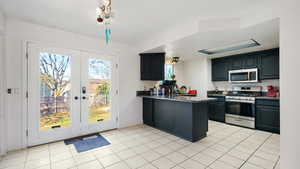 Kitchen featuring a peninsula, stainless steel appliances, dark countertops, french doors, and light tile patterned floors