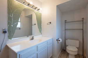 Bathroom with toilet, tile patterned floors, and vanity