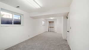 Empty room featuring light colored carpet, visible vents, and baseboards